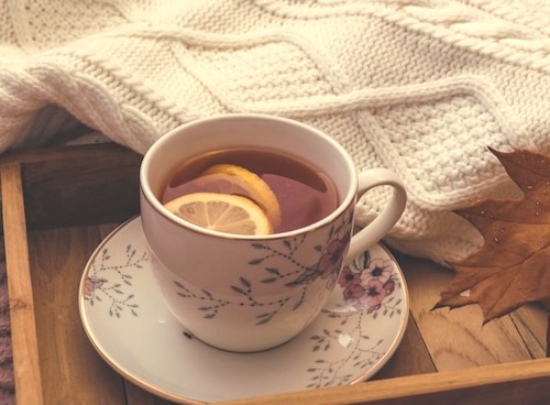 A tray with a cup of lemon tea and a blanket behind it
